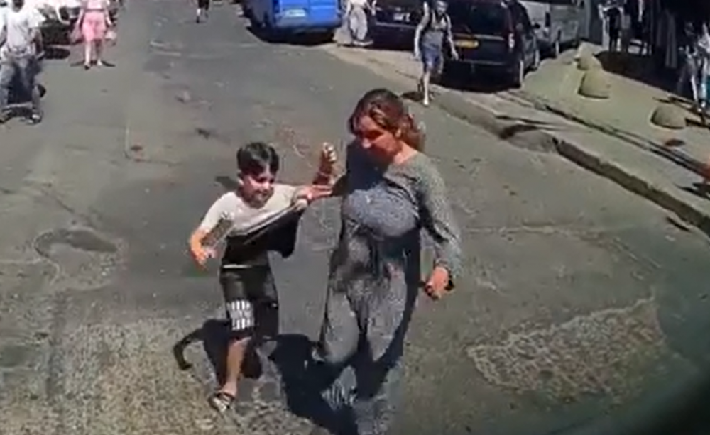 Momentul în care o femeie, împreună cu un copil, încearcă să se lovească de un automobil